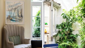 A room with a large window, a chair, and a painting on the wall.