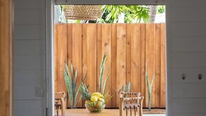 A wooden dining table with chairs, a bowl of fruit, and a hanging plant. - Sweet Cane Tiny House & Pool (Saint-François)