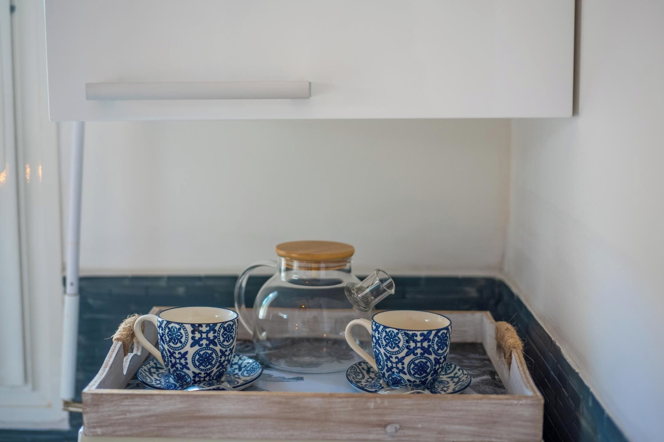 A tray with two blue cups and a glass pitcher on a wooden surface.
