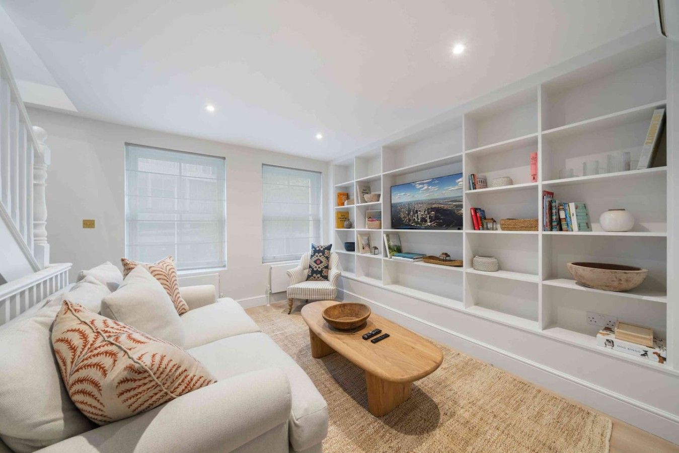 A modern living room with a white sofa, a wooden coffee table, and a built-in bookshelf.