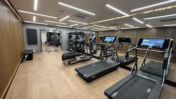 A modern gym with treadmills, exercise bikes, and weight machines.