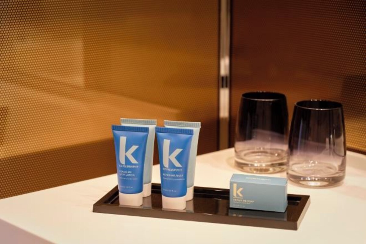 Habitación de hotel con una bandeja que contiene dos tubos azules, dos vasos transparentes y una pequeña caja.