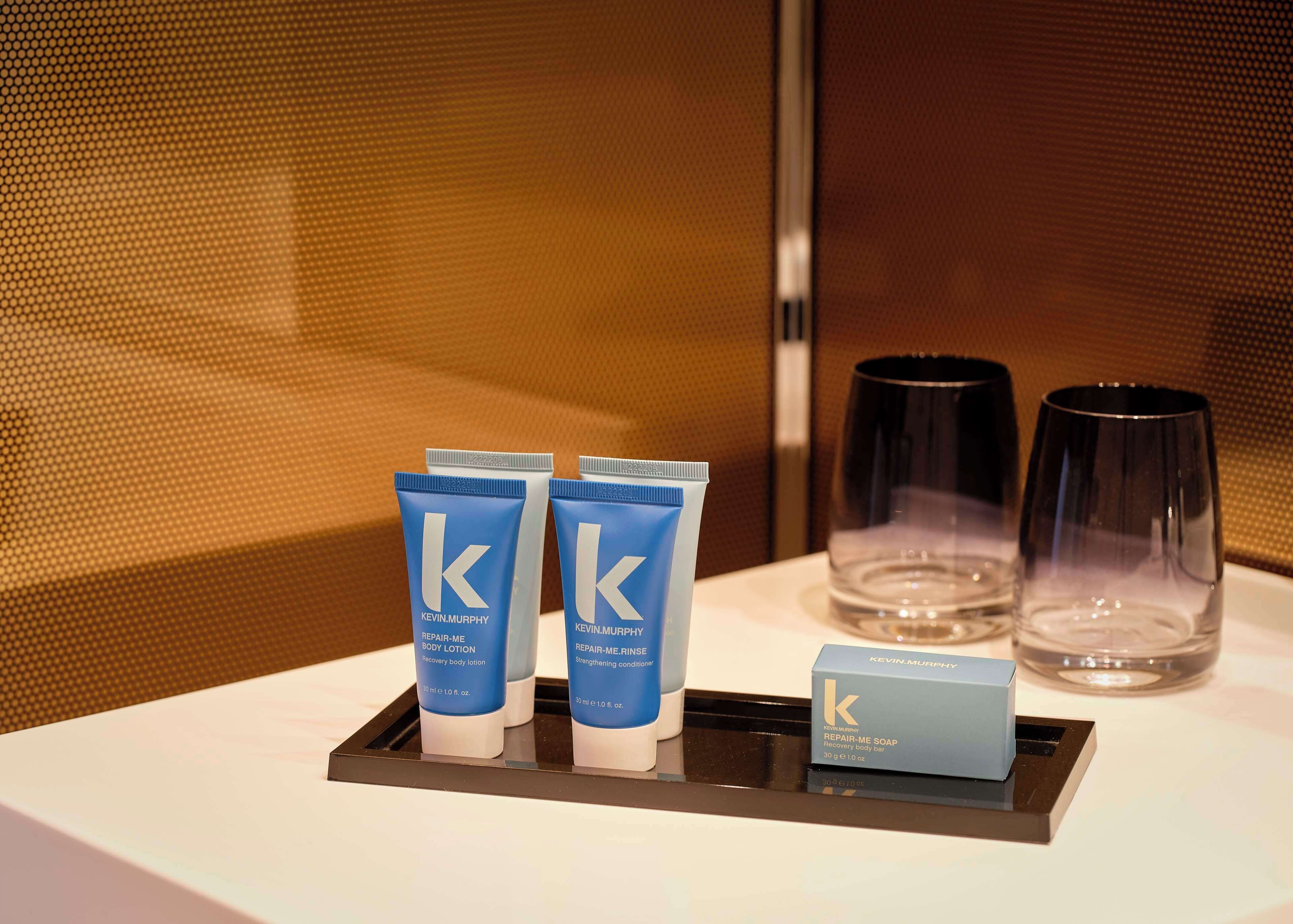 A tray with three Kevin Murphy body care products, two glasses, and a bar of soap.