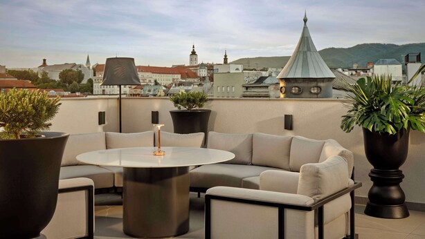 Een dakterras met een ronde tafel, een bank en potplanten.