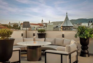 Una terraza en la azotea con una mesa redonda, un sofá y plantas en macetas.