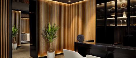 A modern interior with a wooden panel wall, a black fireplace, and white chairs.