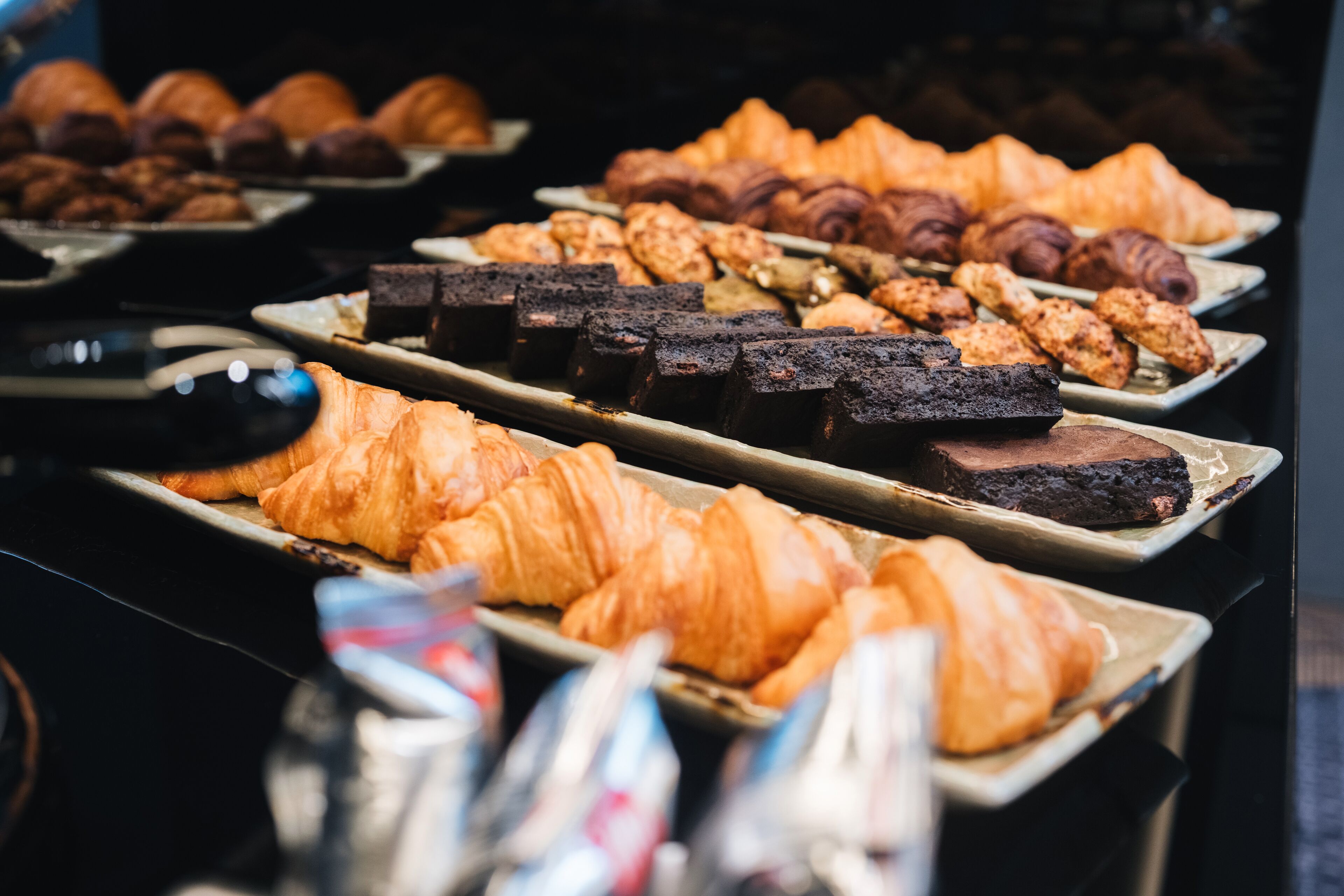 Une grande variété de viennoiseries et de desserts sont présentés, notamment des croissants et des brownies.