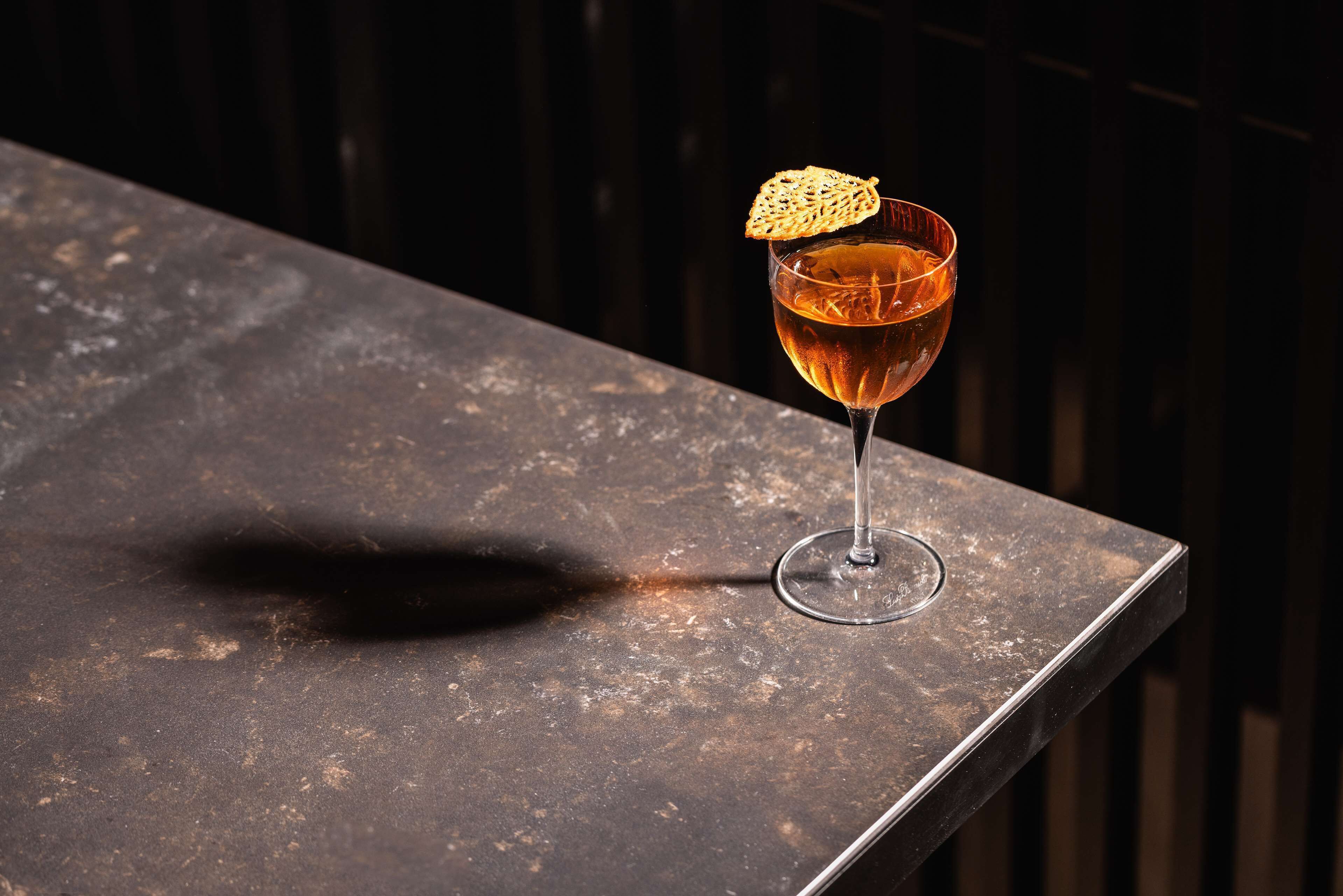 A cocktail glass with a garnish on a textured surface.