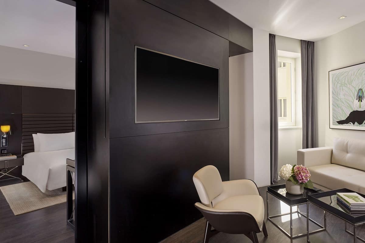 Un salon moderne comprenant un canapé, un fauteuil, une table basse et un téléviseur à écran plat fixé au mur.