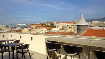 Une terrasse sur le toit avec un espace bar, des sièges et une vue sur le paysage urbain.