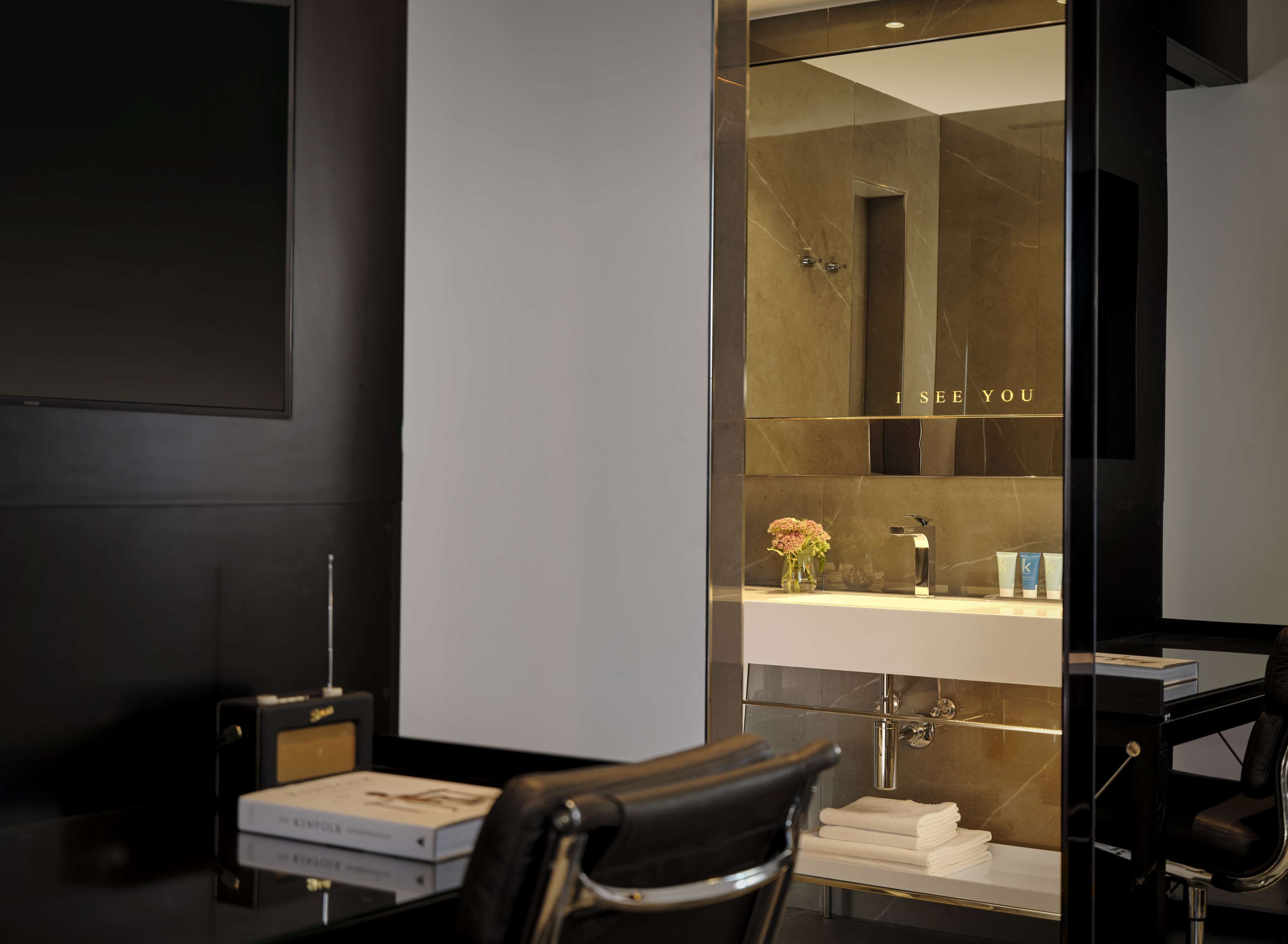 A modern bathroom with a glass shower enclosure, a vanity with a mirror, and a chair.