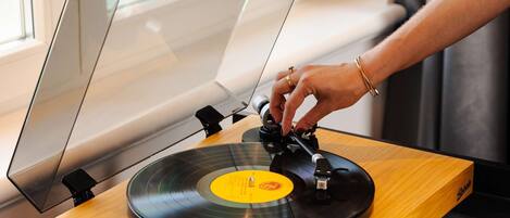 A turntable with a wooden base and a transparent cover, placed on a glass table.
