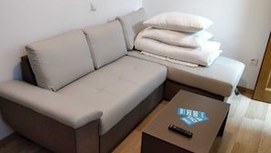Un salon moderne avec un canapé, des coussins et une table basse sur laquelle se trouve une télécommande.