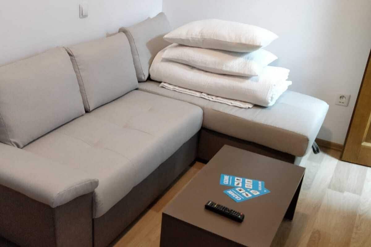 A modern living room with a sofa, pillows, and a coffee table with a remote control.