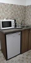 Cocina compacta con un microondas Haier blanco, un refrigerador pequeño y un lavamanos con grifo.