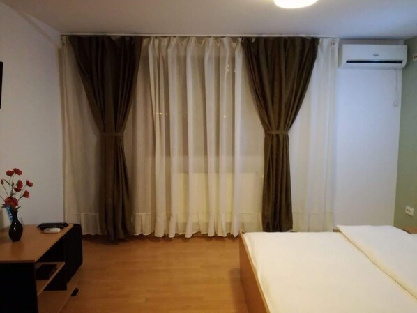 A room with a bed, a desk, a vase with flowers, and curtains. - Cazare Business-Transit (Balotesti)