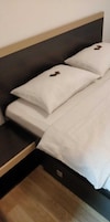 Una cama con ropa blanca y un cabecero oscuro.