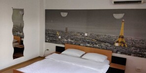 A bedroom with a bed, a wall-mounted air conditioner, and a cityscape mural featuring the Eiffel Tower. - Cazare Business-Transit (Balotesti)