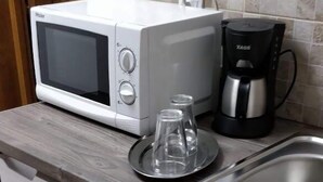 Une cuisine compacte équipée d’un four à micro-ondes, d’une machine à café et d’un petit évier.
