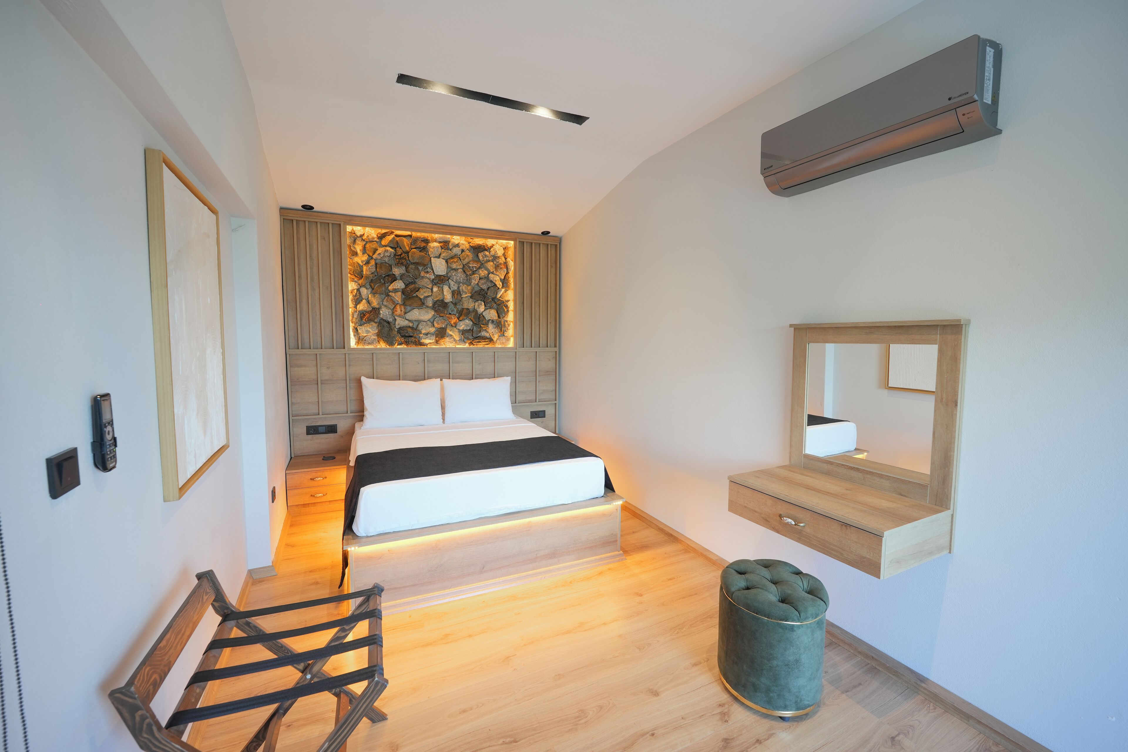 A modern bedroom with a bed, bedside tables, a mirror, and an air conditioning unit.