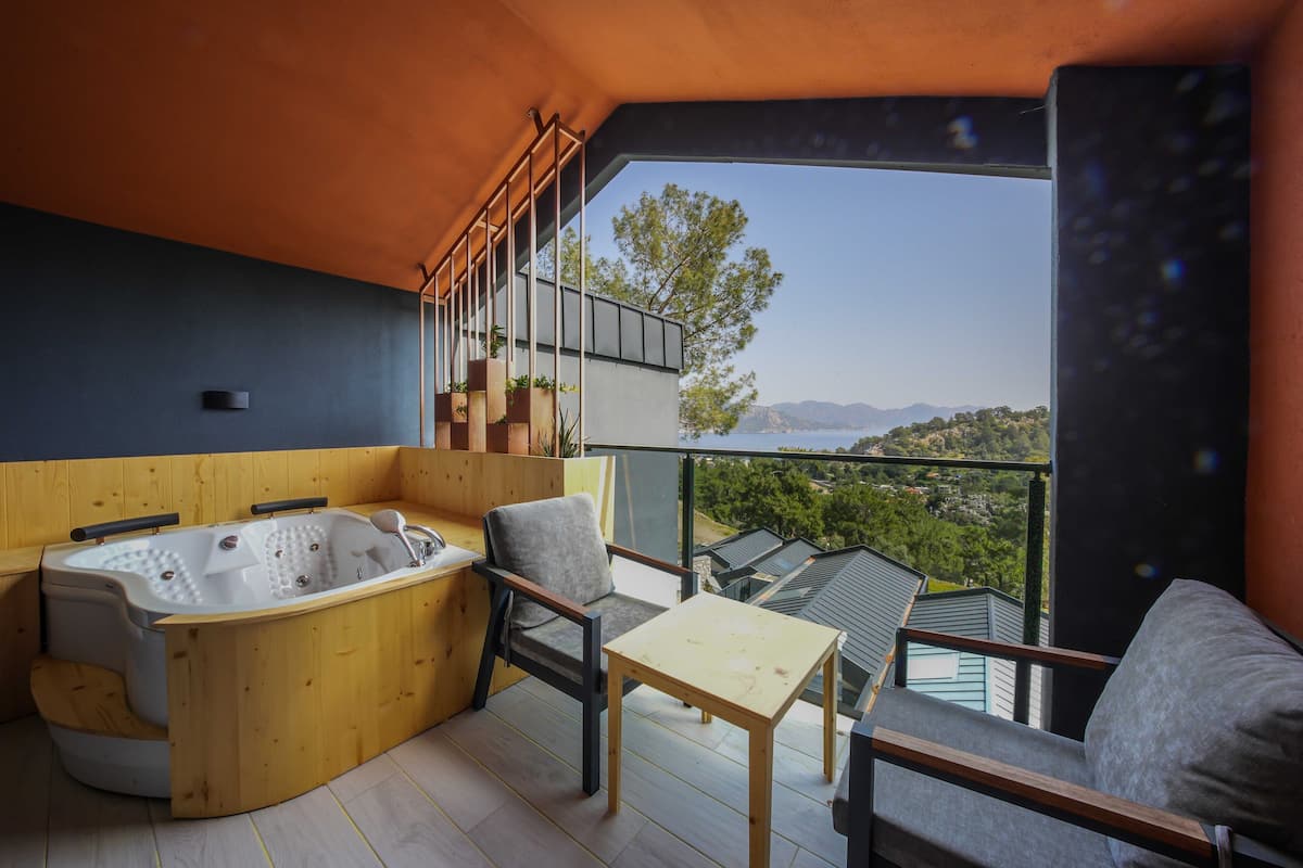 A balcony with a hot tub, seating, and a table.