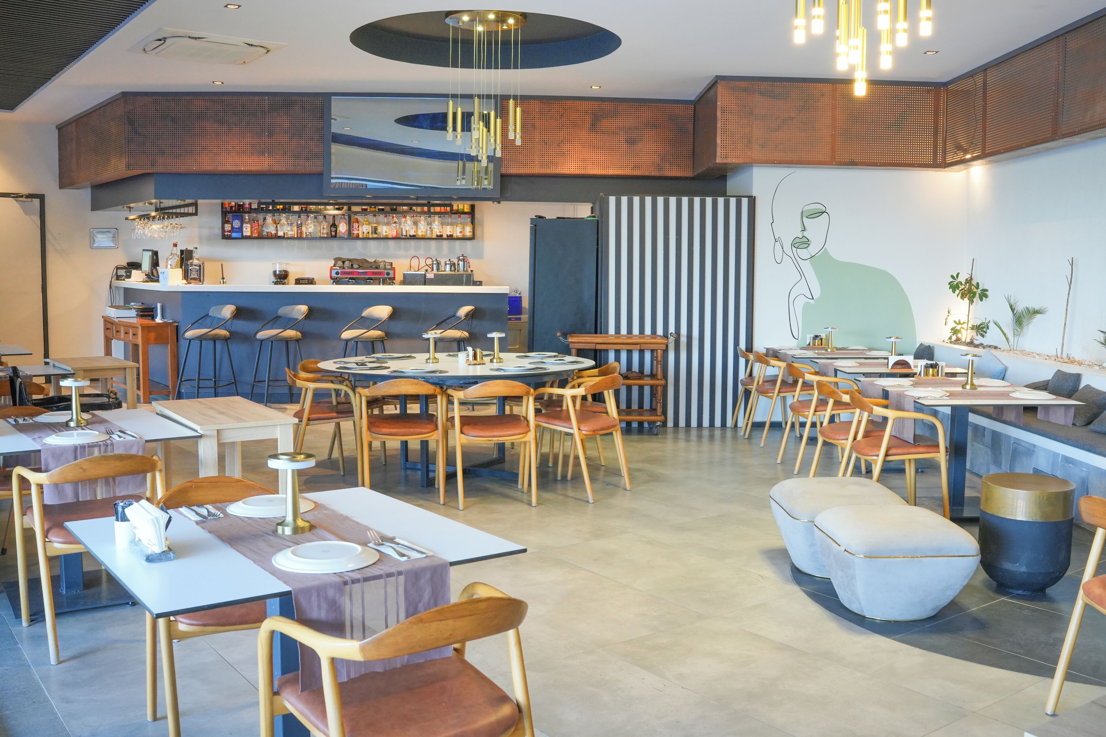 Ein modernes Restaurant mit Bar, mehreren Tischen und Stühlen sowie einem zeitgemäßen Interieur.