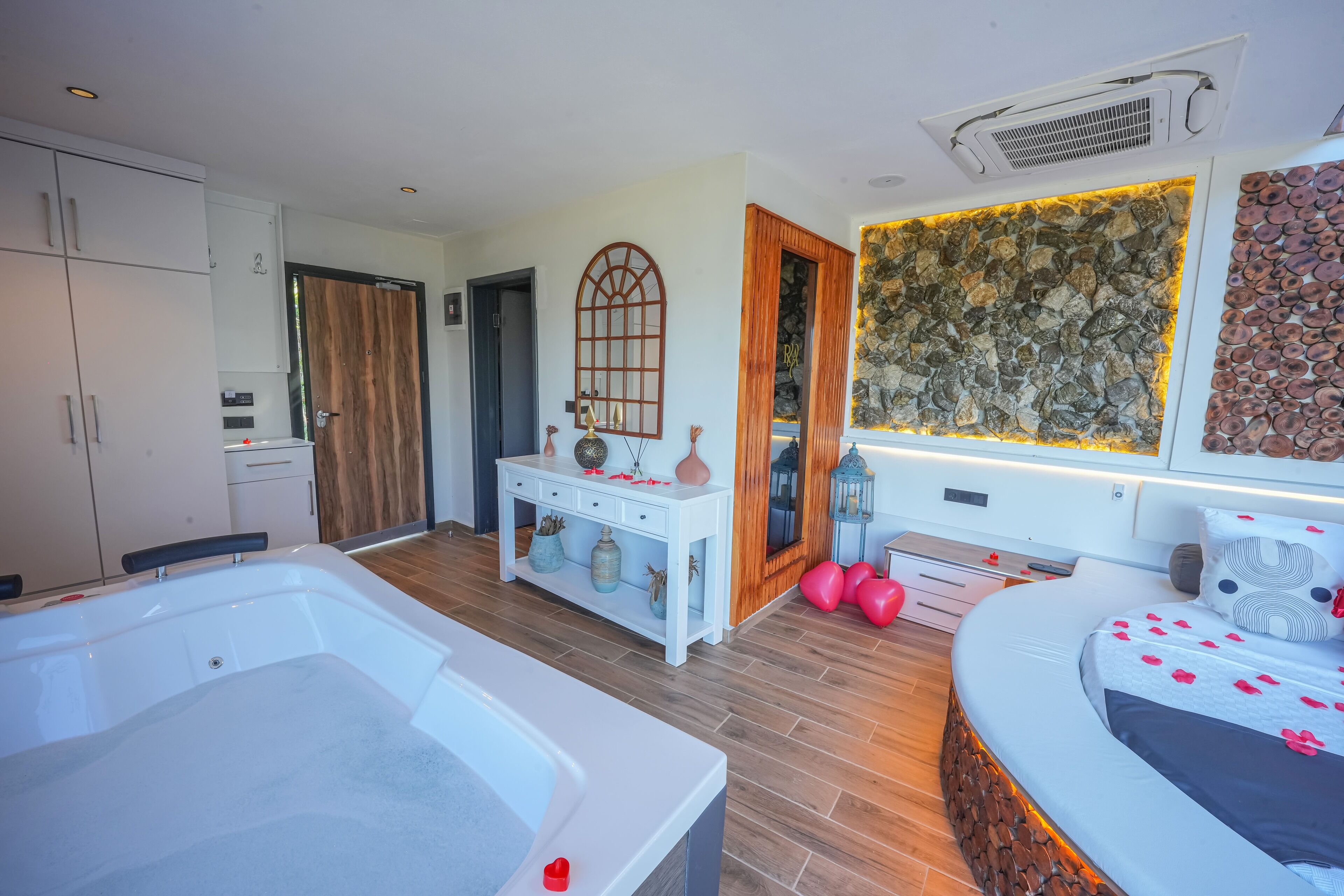 A modern bedroom with a large bed, a bathtub, and a vanity with decorative items.