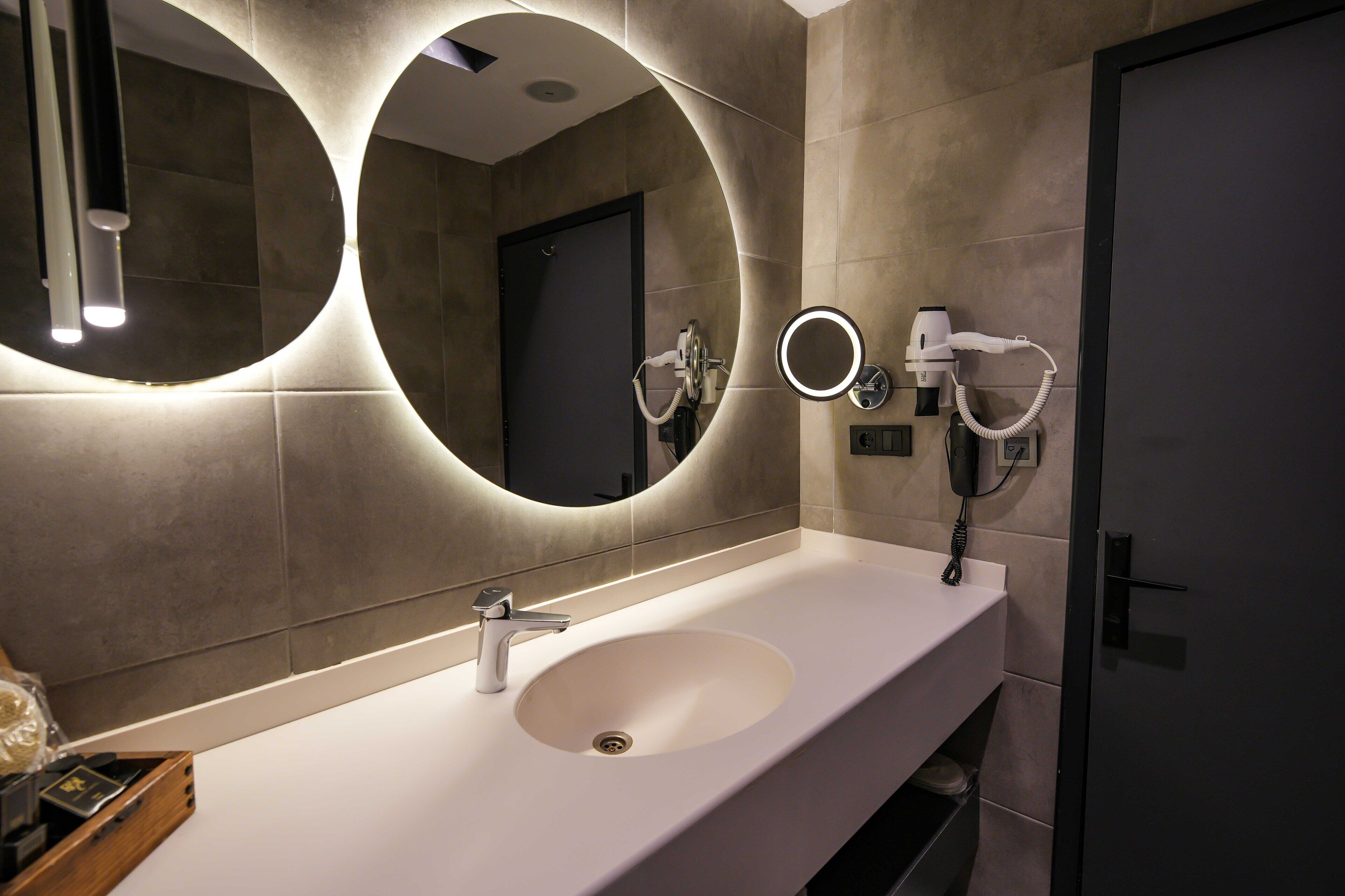 Un baño moderno con un espejo grande, un secador de pelo y un perchero para toallas.
