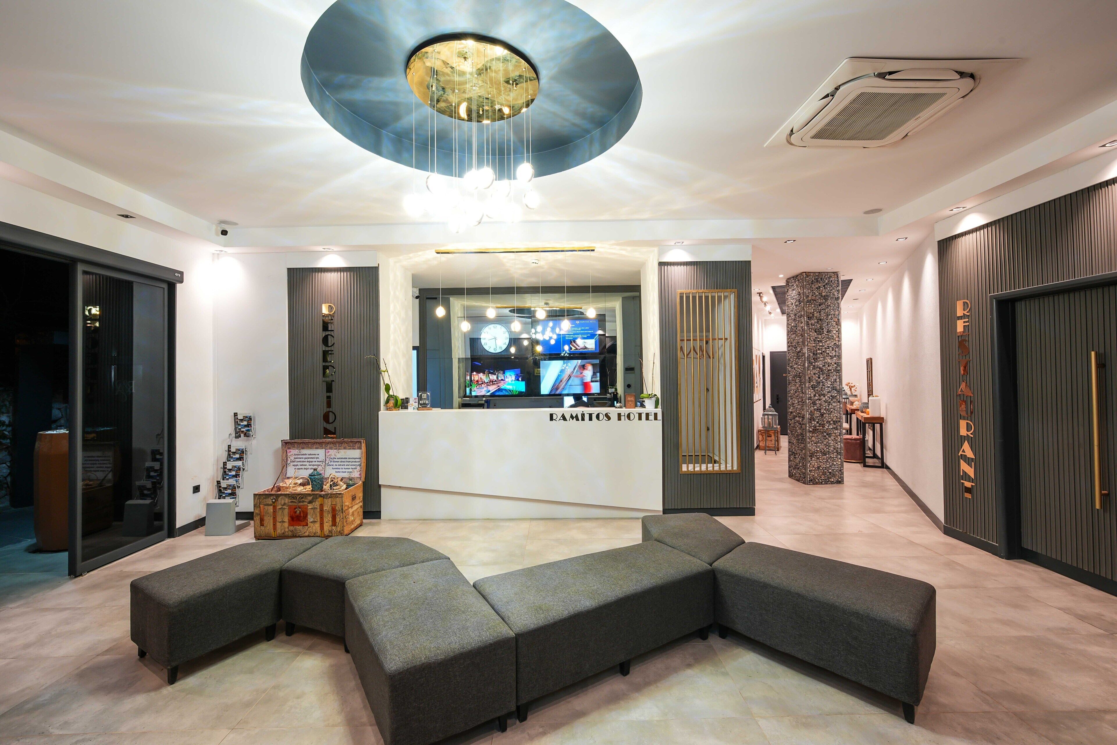 A modern hotel lobby with a reception desk, seating area, and a unique ceiling design.