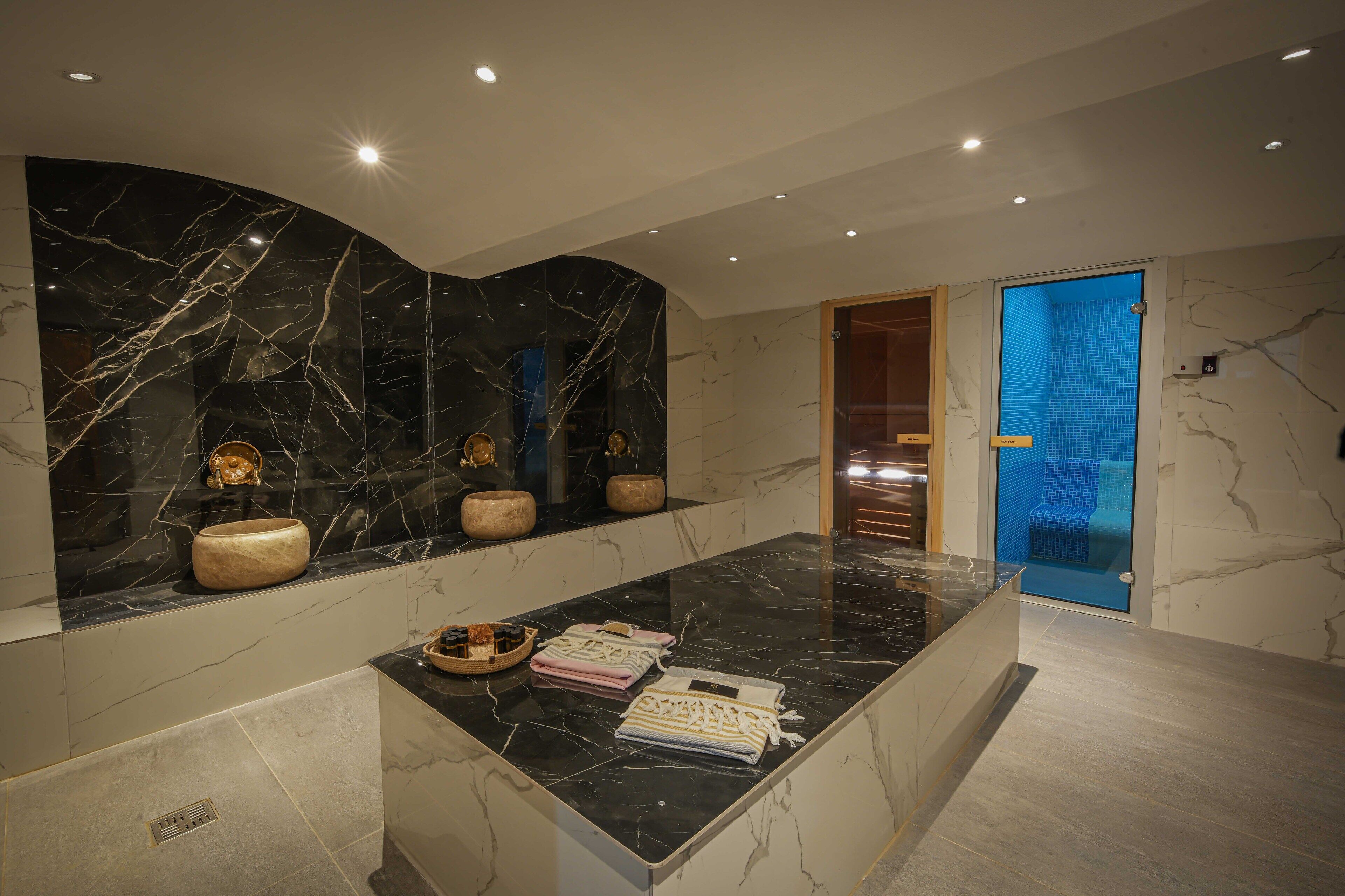 A modern bathroom with a marble vanity, a glass shower enclosure, and a sink with toiletries.