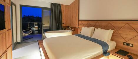 Una habitación de hotel moderna con una cama grande, mesitas de noche y vistas al área exterior.