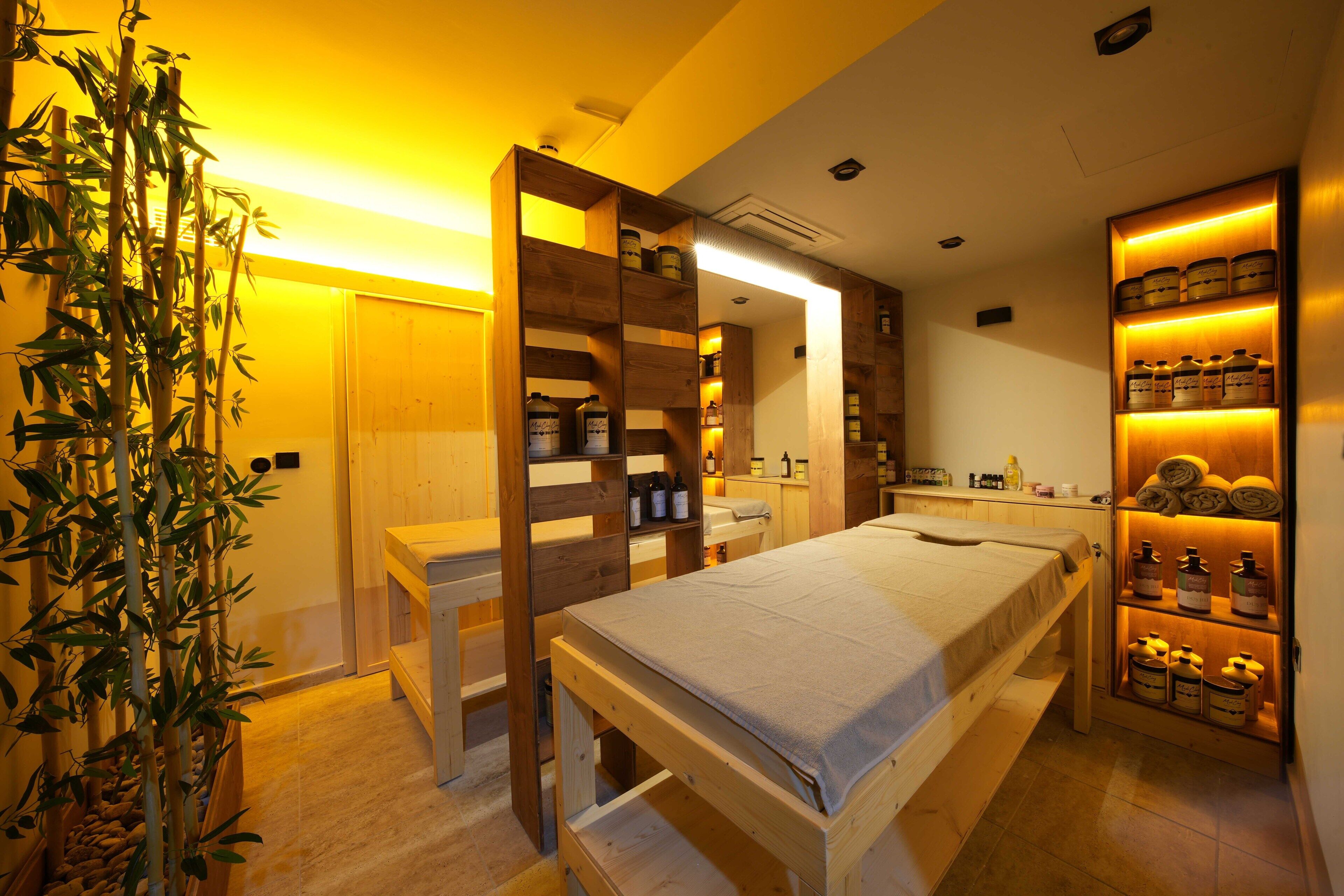 Ein Schlafzimmer mit einem Bett, Nachttischen, einer Holzwand mit Flaschen und einer Topfpflanze.