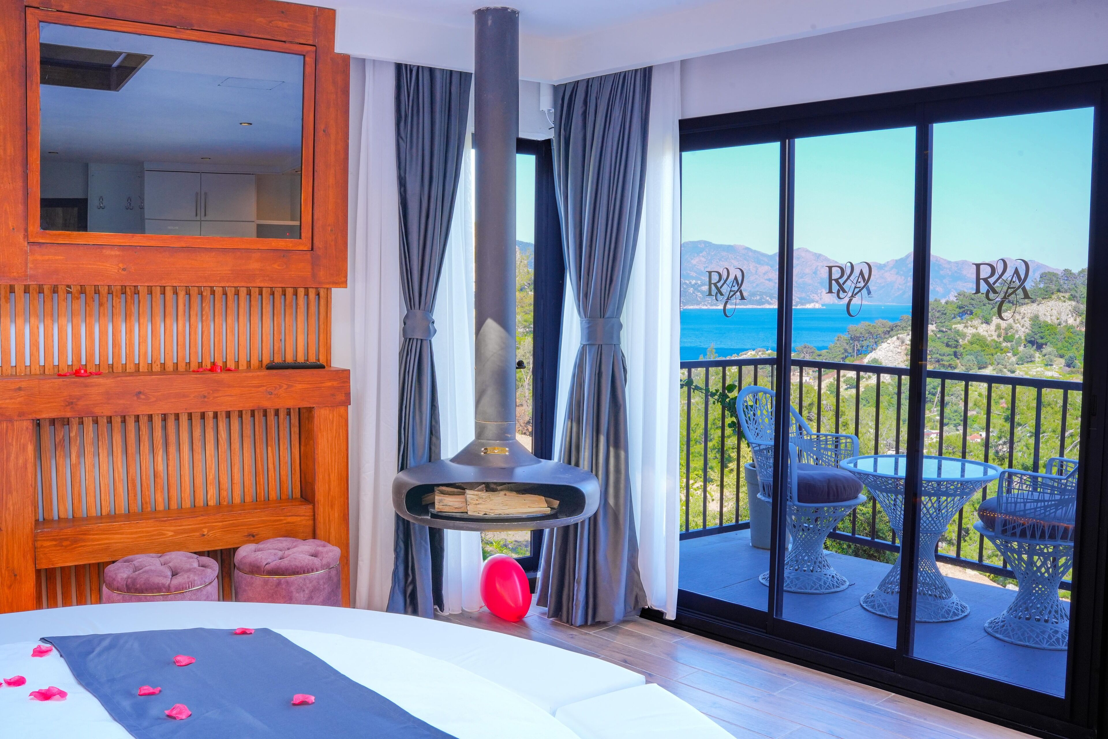 Een slaapkamer met een groot raam, een open haard en een balkon met tuinmeubilair.