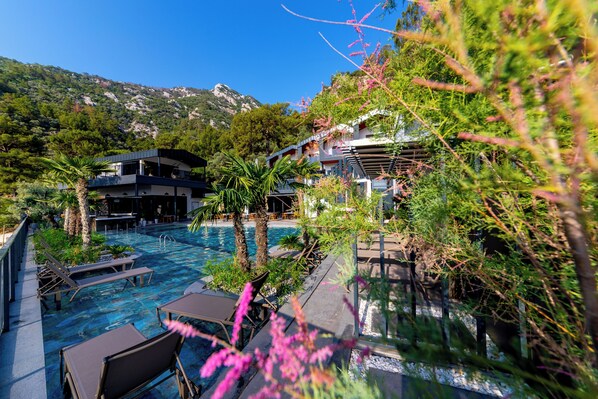 Área da piscina com espreguiçadeiras e vista para uma montanha.