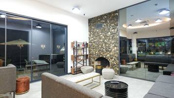 Un espace de vie moderne agrémenté d’un mur en pierre, d’une cheminée et d’une cloison en verre.