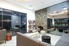 Uma sala de estar moderna com uma parede de destaque em pedra, lareira e divisória de vidro.