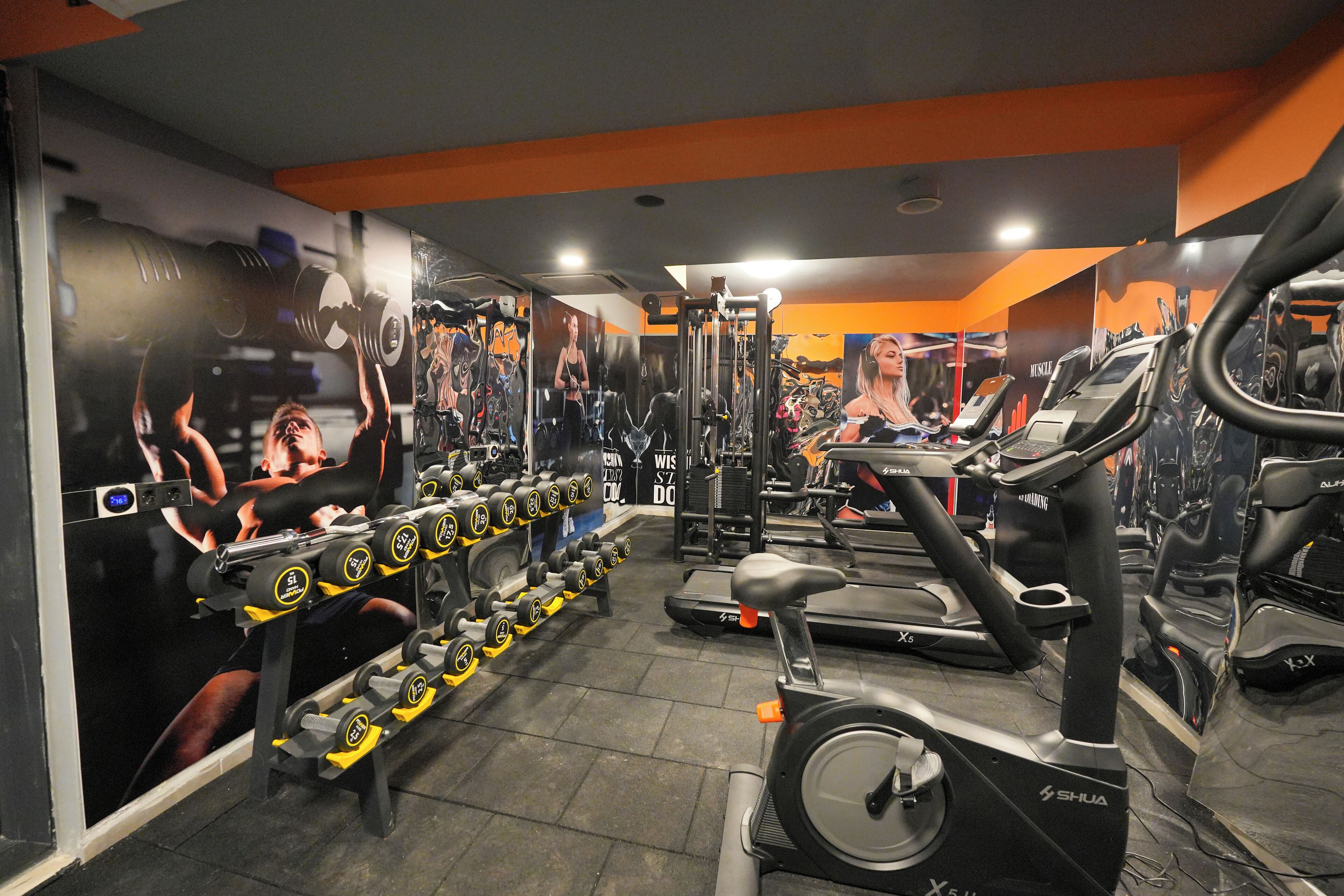 A gym with exercise equipment, including treadmills and dumbbells.