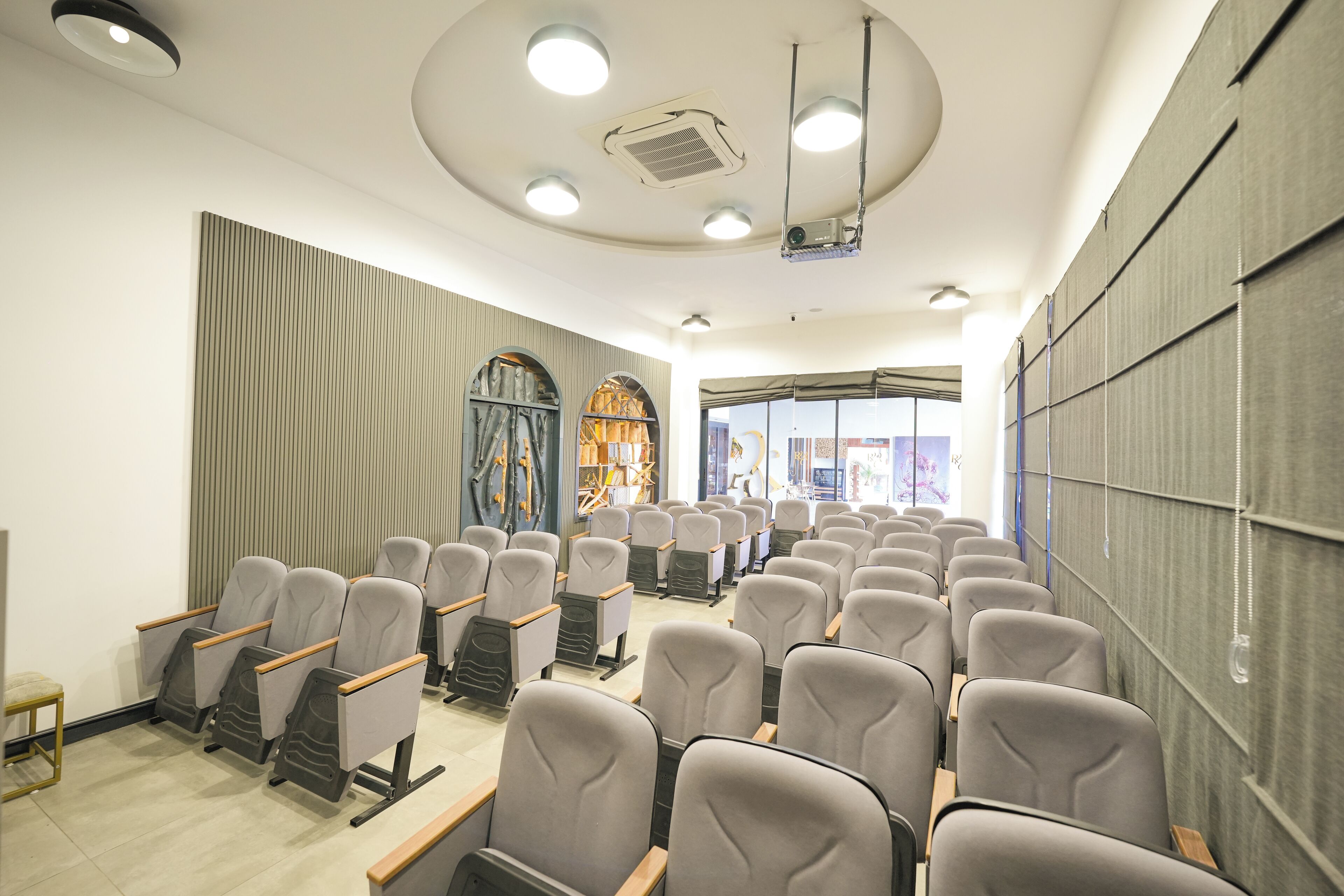 A conference room with rows of chairs, a projector, and a large window with curtains.