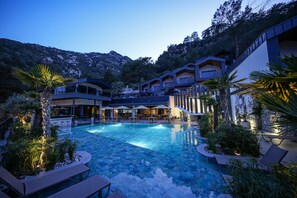 A swimming pool surrounded by lounge chairs and potted plants, with a mountain backdrop and modern buildings. - Ramitos Hotel (Marmaris)