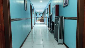 Un pasillo de hotel con paredes azules, puertas de madera y piso de baldosas.