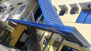 A building with a blue awning, a yellow entrance sign, and a red 'OYO' sign. - Yellow Pad Hotel Davao (Davao)