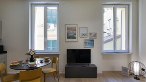 A modern living room with a flat-screen TV, a dining table with chairs, and artwork on the walls. - Riviera Flavour Apartments by Wonderful Italy - Malva (Santa Margherita Ligure)