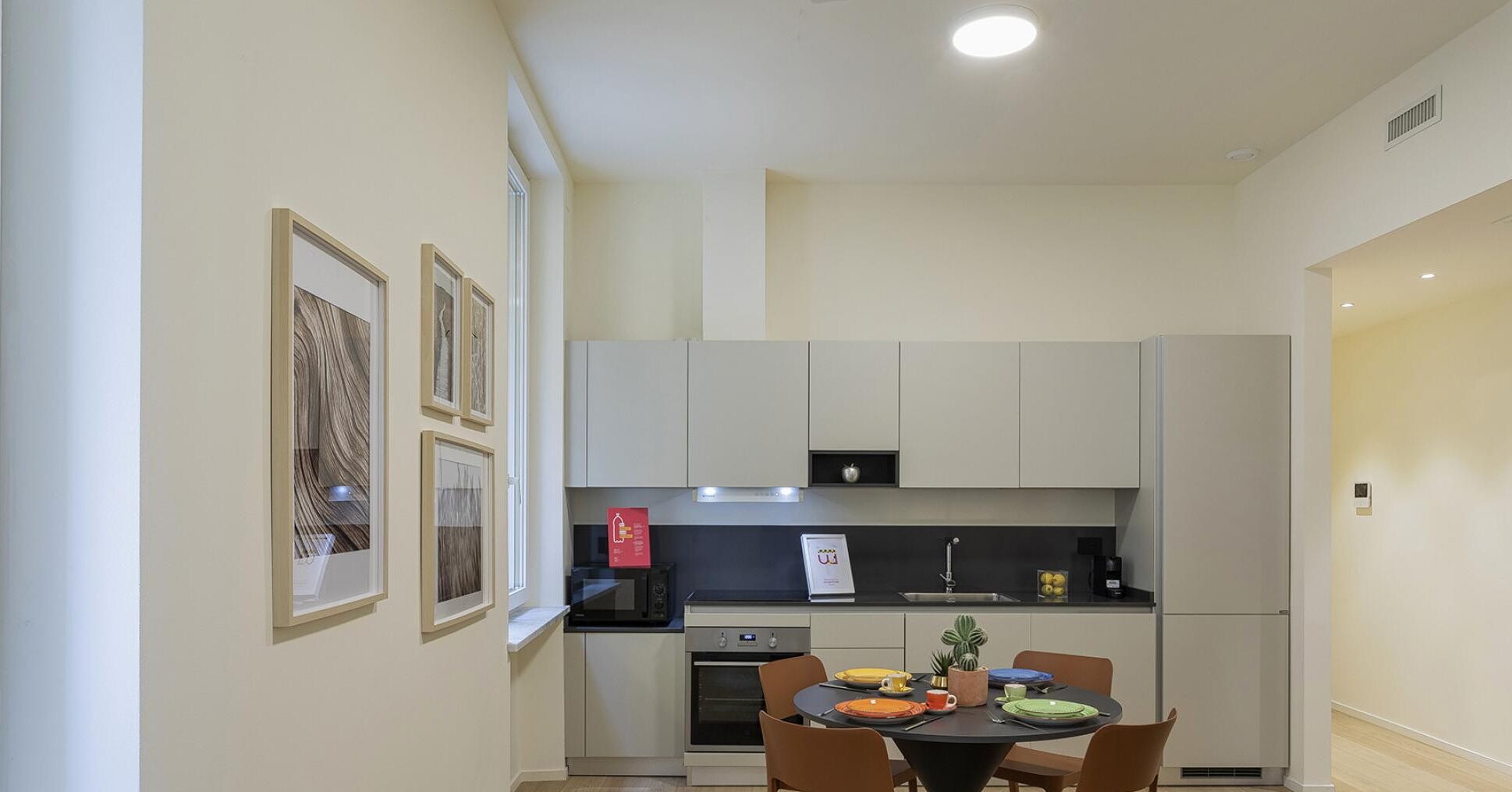 A compact kitchen with white cabinets, a built-in oven, and a dining table with chairs.