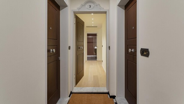Pasillo con puertas de madera, un letrero con el número 3 y suelo alfombrado.