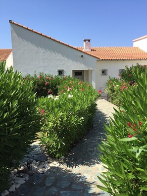 A pathway leading to a building with a tiled roof and white walls.