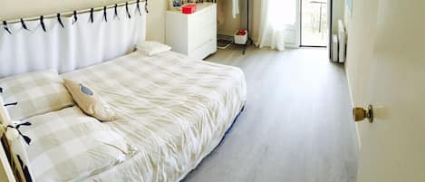 Un dormitorio con una cama, un aparador y una ventana.