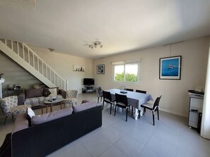 Un salon avec un escalier, un coin repas et un téléviseur.