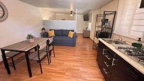 Un espace de vie compact comprenant un coin repas, une kitchenette et un canapé à l’arrière-plan.