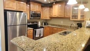 A modern kitchen with granite countertops, stainless steel appliances, wooden cabinets, and pendant lighting. - Quiet, forest view condo at Mabel Lake - Dog friendly! (Enderby)