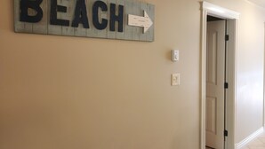 A hallway with a wooden sign reading "BEACH" with an arrow pointing to the right. - Quiet, forest view condo at Mabel Lake - Dog friendly! (Enderby)
